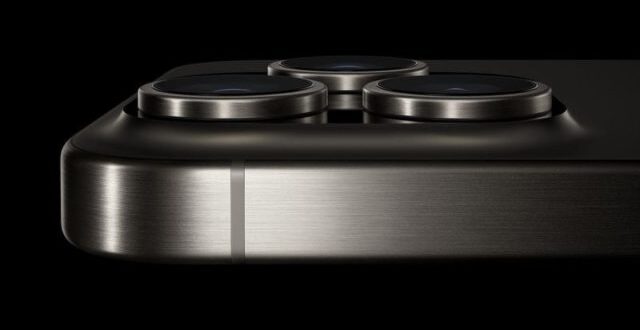 من iPhoneIslam.com، لقطة مقربة لزاوية هاتف آي فون 16 الأنيقة تظهر فيها ثلاث عدسات كاميرا مع تحسينات الكاميرا ولمسة نهائية معدنية على خلفية سوداء.