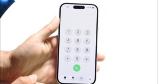 من موقع فون إسلام: يد تحمل هاتفًا ذكيًا يعرض لوحة الاتصال الهاتفي التي تحتوي على لوحة الاتصال الهاتفي مع الأرقام 0-9 والنجمة ومفاتيح الجنيه وزر الاتصال الأخضر - تظهر الميزات الجديدة بعد تحديث iOS 26.